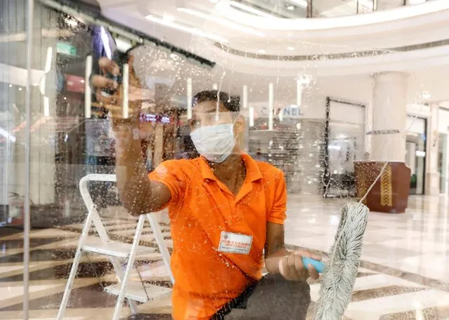 A worker cleans a window of a shop at a mall ahead of its reopening during an extended nationwide lockdown to slow down the spread of the coronavirus disease (COVID-19), in New Delhi, India June 7, 2020. (Photo by Anushree Fadnavis/Reuters)