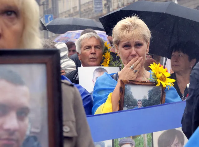 People hold photos of their relatives who were killed as soldiers in the conflict with pro-Russian separatists in the country's east, as they attend a rally for Independence Day in the Ukrainian capital Kiev, Wednesday, August 24, 2016. (Photo by Efrem Lukatsky/AP Photo)