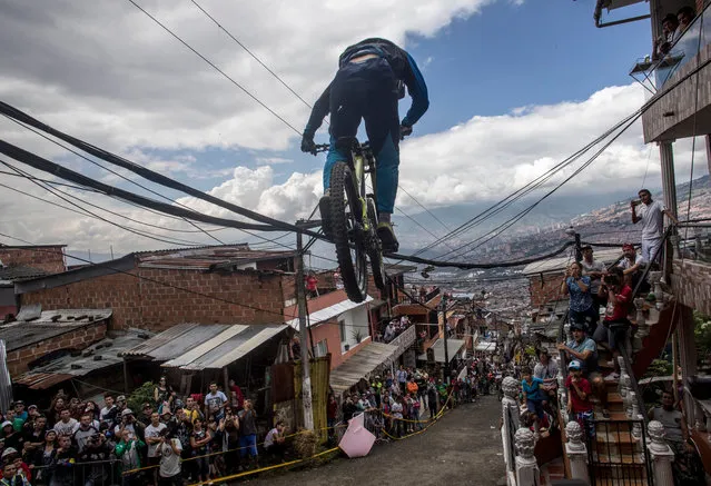 Residents watch as a downhill rider competes during the Urban Bike Inder Medellin race final at the Comuna 1 shantytown in Medellin, Antioquia department, Colombia on November 19, 2017. (Photo by Joaquin Sarmiento/AFP Photo)