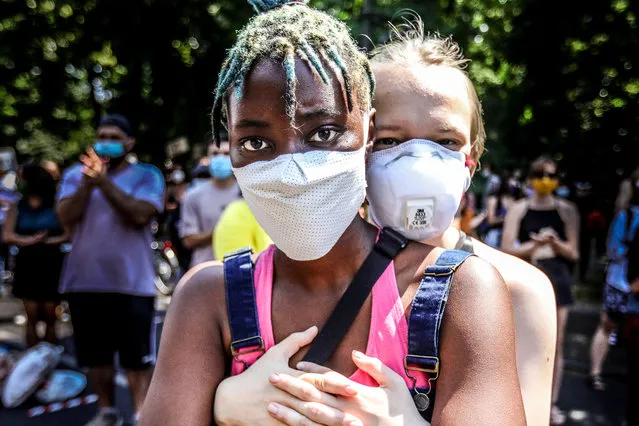 A participant embraces another at a Black Lives Matter (BLM) demonstration in Berlin, Germany, 27 June 2020. A large crowd gathered under the German capital's Victory Column Siegessaeule in protest against racism and in commemoration of the death of George Floyd, an African-American man who died while in Minneapolis police custody on 25 May 2020 after the arresting officer knelt on his neck for more than 8 minutes. (Photo by Omer Messinger/EPA/EFE)
