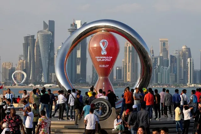 People gather around the official countdown clock showing remaining time until the kick-off of the World Cup 2022, in Doha, Qatar, Friday, November 11, 2022. Final preparations are being made for the soccer World Cup which starts on Nov. 20 when Qatar face Ecuador. (Photo by Hassan Ammar/AP Photo)