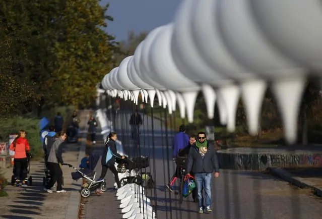 People walk under stands with balloons placed along the former Berlin Wall location at Mauerpark, which will be used in the installation “Lichtgrenze” (Border of Light) in Berlin November 7, 2014. (Photo by Pawel Kopczynski/Reuters)