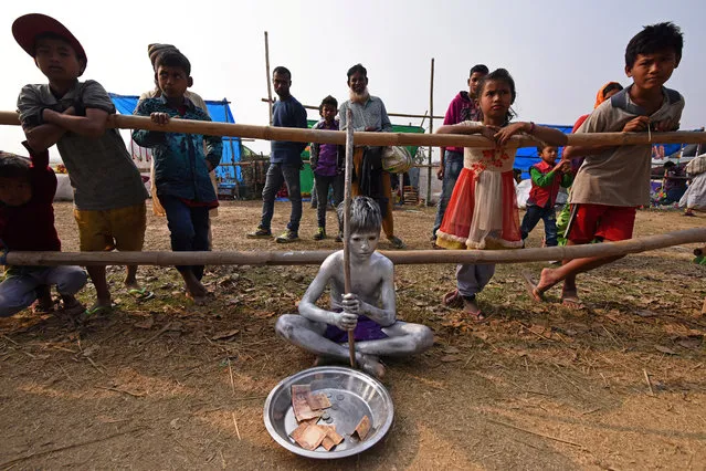 A boy begs for alms at the Jonbeel Mela festival, where people belonging to different tribes exchange their merchandise with locals through a barter system, in the Morigaon district, in the northeastern state of Assam, India on January 19, 2018. (Photo by Anuwar Hazarika/Reuters)