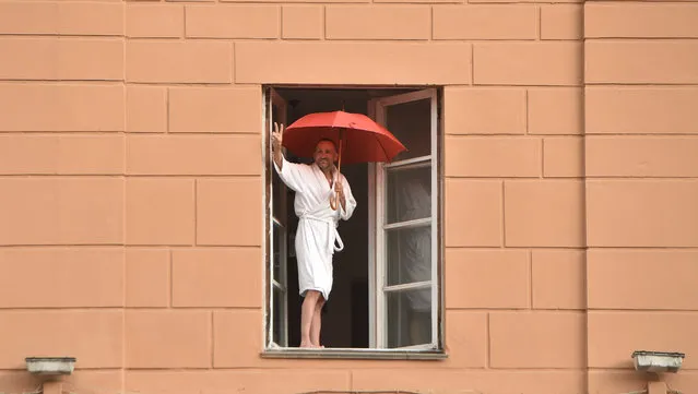 A Belarus opposition supporter raises a V-sign from his window as he welcomes a rally to protest against disputed presidential elections results in Minsk on August 27, 2020. (Photo by Sergei Gapon/AFP Photo)