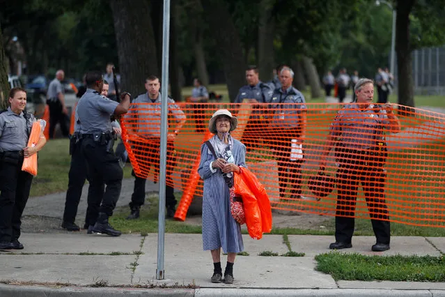 An elderly woman waits for the bus as members of the Milwaukee County Sheriff's department erect a fence around Sherman Park after disturbances following the police shooting of a man in Milwaukee, Wisconsin, U.S. August 15, 2016. (Photo by Aaron P. Bernstein/Reuters)