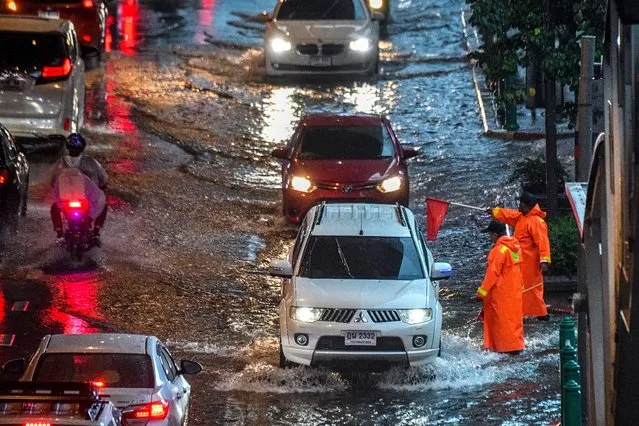 Security guards regulate traffic on a flooded road during a heavy rain in Bangkok on September 23, 2020. (Photo by Mladen Antonov/AFP Photo)