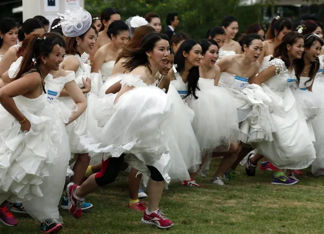 Brides to-be run as they participate at the “Running of the Brides” event in Bangkok, Thailand, November 29, 2014. Some sixty five couples attended the event in hope of winning 30,437 US dollars (one million Thai Baht) prize on a dream wedding package. (Photo by Narong Sangnak/EPA)
