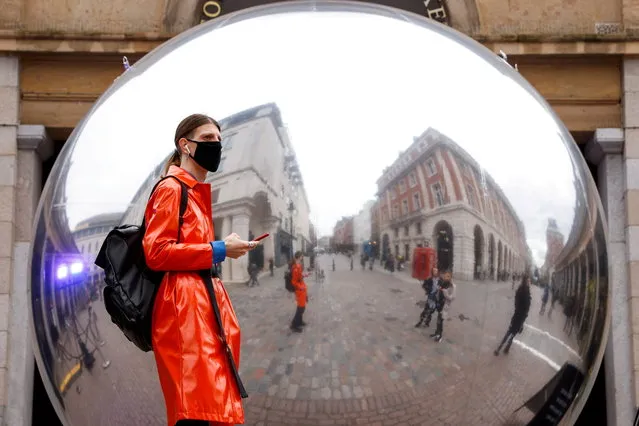 A person wearing a face mask is reflected in an art work entitled “A=V” by Ben Cullen Williams, amid the coronavirus disease (COVID-19) outbreak, in Covent Garden, London, Britain on October 16, 2020. (Photo by John Sibley/Reuters)