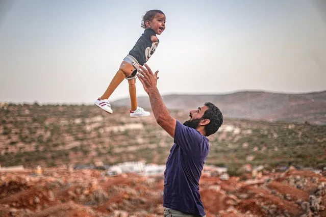 Father Khalid Mosaitef (R) throws his 15-month-old congenital amputee son Mohammad Mosaitef (L) into the air in Idlib, Syria on October 21, 2020 following Mohammad's 7-week adaptation process for his prosthesis legs. Mosaitef family fled the civil war in Syria and sheltered at a camp with a tent of their relatives in Idlib. Family received help for their congenital amputee child in Turkey. Mohammad child returned to Idlib with his new prosthesis legs. (Photo by Muhammed Said/Anadolu Agency via Getty Images)