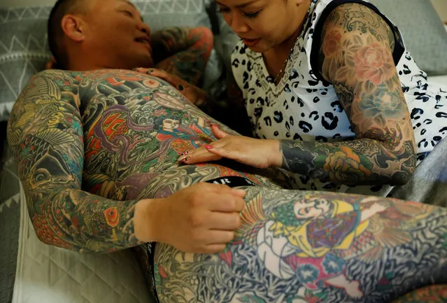 Bookkeeper Mina Yoshimura, 40, who works at her husband Hiroshi Yoshimura's company, touches a new tattoo that Hiroshi Yoshimura got on the same day, at their home in Tokyo, Japan, October 2, 2020. “Well, if I had tattoos and he didn't, he'd be able to go places that I couldn't. But since we're both the same, we can go anywhere together. I think that's nice”, said Mina, as she spoke about Hiroshi. (Photo by Kim Kyung-Hoon/Reuters)