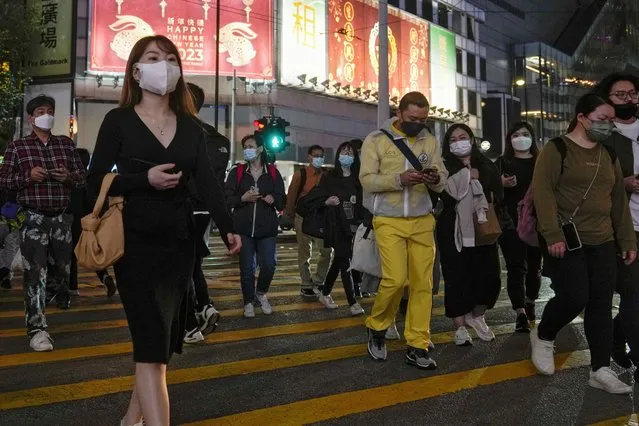 People wearing face masks walk across a busy street at the Causeway Bay shopping district in Hong Kong on February 7, 2023. Hong Kong’s government announced Thursday, Feb. 16, that the territory's population dropped for a third straight year as deaths rose during the pandemic and anti-virus measures reduced the number of arriving workers, but did not mention an exodus of residents sparked by a crackdown on the pro-democracy movement. (Photo by Andy Wong/AP Photo)