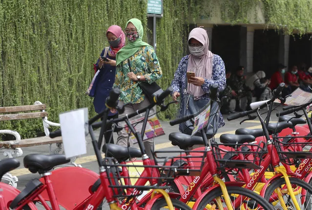 Indonesian women wearing masks as a precaution against the coronavirus outbreak walk on a pedestrian street in Jakarta Monday, October 12, 2020. (Photo by Achmad Ibrahim/AP Photo)