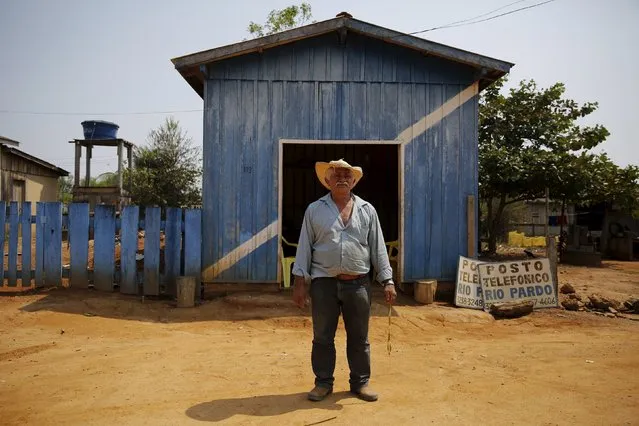 Francisco Morais, 69, poses in front of a public phone that he owns in Rio Pardo next to Bom Futuro National Forest, in the district of Porto Velho, Rondonia State, Brazil, August 31, 2015. The placard (R) reads "Rio Pardo, Public Phone". (Photo by Nacho Doce/Reuters)