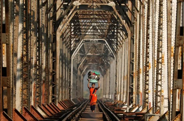 Woman carrying luggage walks along a railway track on the outskirts of Mumbai, India on November 12, 2020. (Photo by Francis Mascarenhas/Reuters)