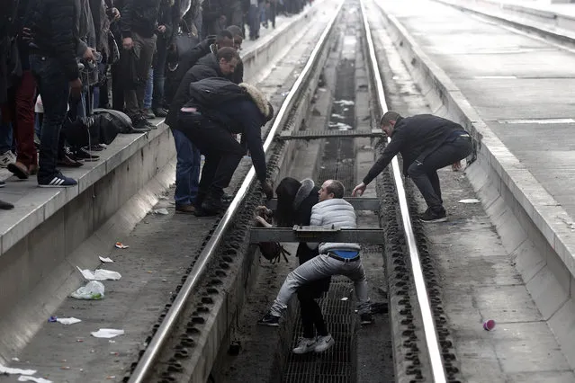 Passengers assist a woman who fell off a platform as she was trying to cross railroad tracks at Gare de Lyon train station, in Paris, as unions stage a mass strike, Tuesday, April 3, 2018. A major French railway strike has brought the country's famed high-speed trains to a halt, leaving passengers stranded and posing the biggest test so far for President Emmanuel Macron's economic strategy. (Photo by Francois Mori/AP Photo)