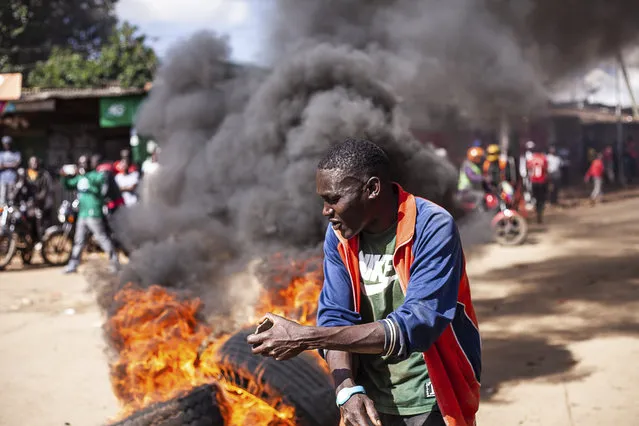 A protesters reacts next to a burning barricade during a mass rally called by the opposition leader Raila Odinga over the high cost of living in Kibera Slums, in Nairobi, Monday, March 27, 2023. (Photo by Samson Otieno/AP Photo)