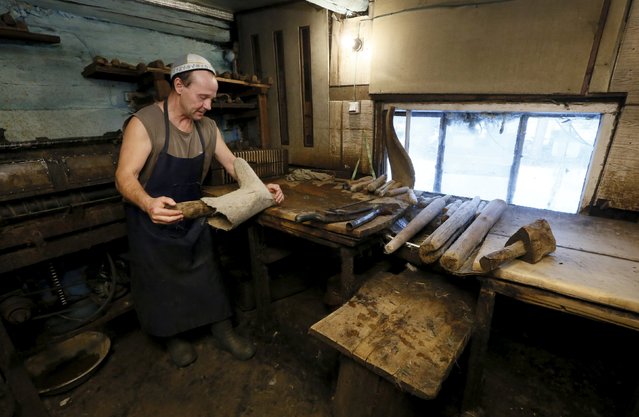 Ivan Plakhuta, 54, the owner of a small workshop manufacturing valenki, Russian traditional footwear, rolls a valenok in the remote Siberian village of Bolshaya Rechka, located in Taiga area in the foothills of the Western Sayan Mountain Ridge in the Yermakovsky district of Krasnoyarsk region, Russia, November 10, 2015. (Photo by Ilya Naymushin/Reuters)