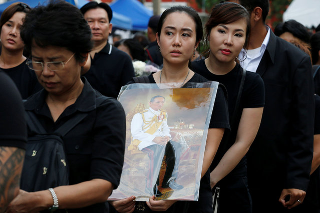 A mourner holds up a picture of Thailand's late King Bhumibol Adulyadej as she waits in line to pay respects to him outside the Grand Palace in Bangkok, Thailand, October 19, 2016. (Photo by Chaiwat Subprasom/Reuters)