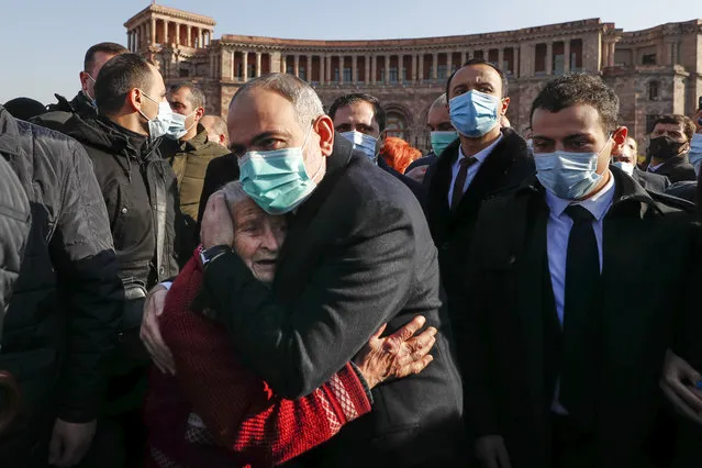 Armenian Prime Minister Nikol Pashinyan comforts a woman during a march of remembrance of the heroes killed in a war over the Nagorno-Karabakh region, in Yerevan, Armenia, Saturday, December 19, 2020. Both opponents and supporters of Armenia's prime minister rallied Saturday as the nation paid tribute to the thousands who died in fighting with Azerbaijan over the region of Nagorno-Karabakh. Critics demanded that the leader resign and tried to pelt him with eggs. (Photo by Tigran Mehrabyan/PAN Photo via AP Photo)