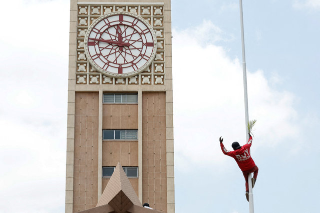 A mourner climbs a pole outside the Parliament building where the body of Kenya’s former Prime Minister Raila Odinga, who had been receiving treatment in India when he died, is expected to be kept for people to pay tribute, in Nairobi, Kenya on October 16, 2025. (Photo by Monicah Mwangi/Reuters)