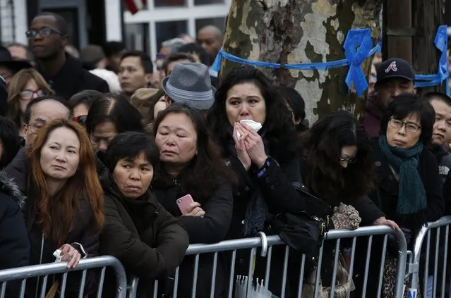 Mourners cram together on the sidewalk to listen to the funeral service for New York Police Department officer Wenjian Liu in the Brooklyn borough of New York January 4, 2015. (Photo by Mike Segar/Reuters)