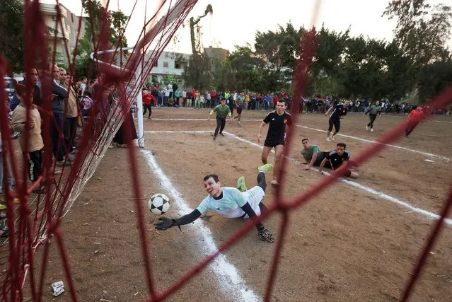 A goalkeeper tries to catch the ball during the annual Ramadan soccer tournament match on a dirt field at the Kafr Abd al Mu'min village before an Iftar (breaking fast) meal during the holy month of Ramadan in Dikirnis, Egypt on April 13, 2023. (Photo by Amr Abdallah Dalsh/Reuters)