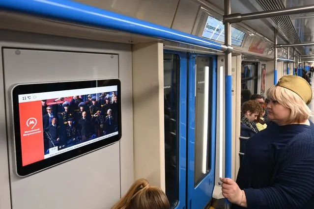 Commuters ride in a metro coach as a screen shows a live broadcast of the Victory Day military parade from Red Square, in Moscow on May 9, 2023. (Photo by Kirill Kudryavtsev/AFP Photo)