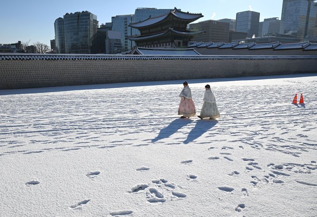 Visitors wearing traditional hanbok dresses walk on the snow-covered grounds of Gyeongbokgung Palace in Seoul on December 5, 2025, after the season's first snowfall. (Photo by Jung Yeon-je/AFP Photo)