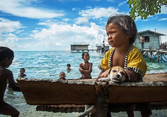 “The beach alone children”. No nationality of Malaysia “Bawo – Rotter” children, with sadness alone on the beach, watching the kids in the game. Location: Malaysia, Semporna. (Photo and caption by He Yuanquan/National Geographic Traveler Photo Contest)