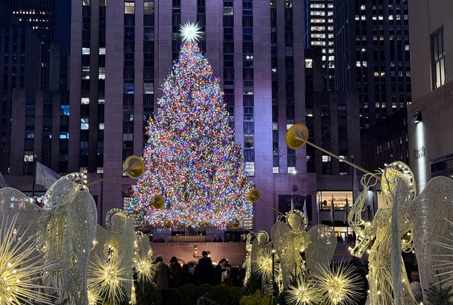 A giant Christmas tree is illuminated as people visit the Rockefeller center during New York City's Fifth Avenue 200th anniversary on December 8, 2024. (Photo by Daniel Slim/AFP Photo)