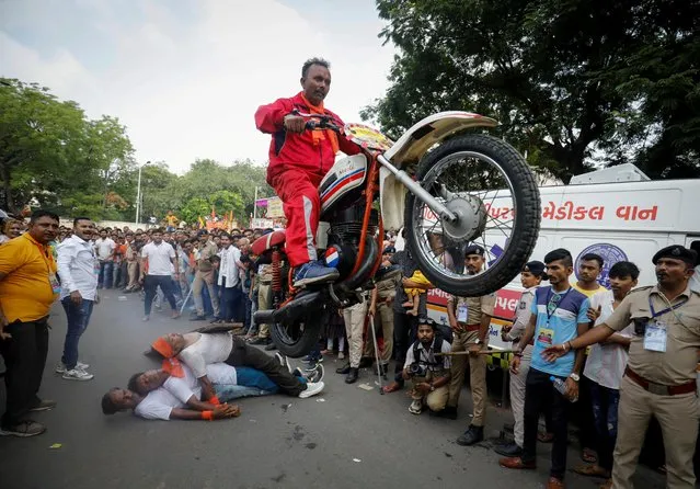 A Hindu devotee performs a stunt with his motorcycle during the annual Rath Yatra, or chariot procession, in Ahmedabad, India on June 20, 2023. (Photo by Amit Dave/Reuters)