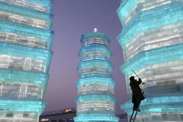 In this Tuesday, December 22, 2015 photo, a man works on an ice sculpture at the Ice and Snow World during a soft opening of the exhibit in Harbin in northeastern China's Heilongjiang province. The annual collection of snow and lighted ice sculptures is a major tourist draw to the city during the winter months. (Photo by Chinatopix via AP Photo)