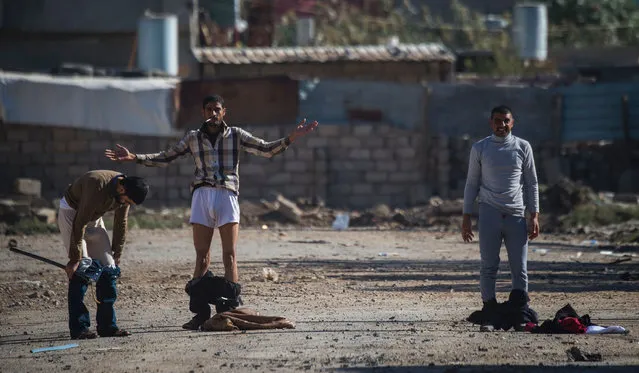 Iraqi men drop their pants before being allowed to approach a position held by the Iraqi Special Forces' second division in Mosul's eastern district of Karkukli on November 18, 2016, during a massive operation to oust Islamic State group jihadists from the country's second city. (Photo by Odd Andersen/AFP Photo)