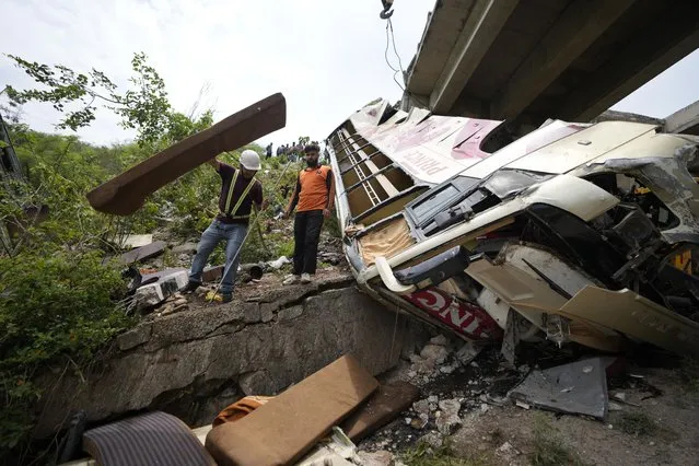 Jammu & Kashmir State Disaster Response Force (SDRF) personnel inspect the wreckage after a bus carrying Hindu pilgrims to a shrine skid off a highway bridge into a Himalayan gorge near Jammu, India, Tuesday, May 30, 2023. (Photo by Channi Anand/AP Photo)
