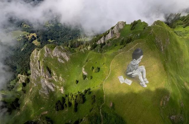 A land art painting representing a child drawing, by Swiss-French artist SAYPE, is pictured at the Chamossiare in Villars-sur-Ollon, Switzerland on July 13, 2023. (Photo by Denis Balibouse/Reuters)