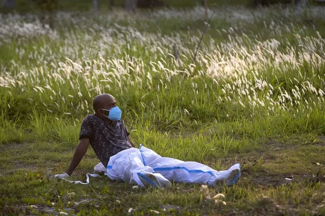 An exhausted municipal worker rests after bringing the body of a person who died of COVID-19 for burial in Gauhati, India, Sunday, April 25, 2021. As India suffers a bigger, more infectious second wave with a caseload of more than 300,000 new cases a day, the country’s healthcare workers are bearing the brunt of the disaster. (Photo by Anupam Nath/AP Photo)