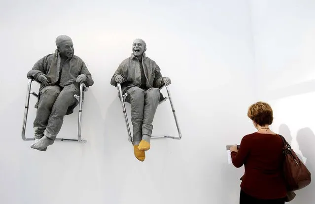 A visitor looks at “2 Seated on the Wall with Big Chairs” by artist Juan Munoz during the International Contemporary Art Fair at the Grand Palais in Paris, on Oktober 23, 2013. (Photo by Benoit Tessier/Reuters)