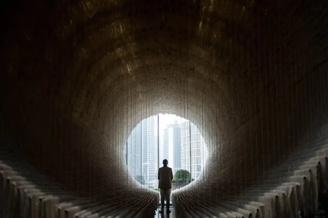 A man looks out from the inside section of Chinese artist Zhu Jinshi's “Boat” art installation at The Rotunda in Hong Kong on March 14, 2015, on the sidelines of Art Basel, the city's largest art fair. The piece comprises of an 18-metre long, 7-metre high installation composed of bamboo, cotton and over 12,000 sheets of xuan (rice) paper. (Photo by Anthony Wallace/AFP Photo)