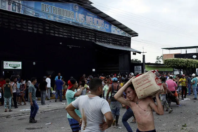 People carry goods taken from a food wholesaler after it was broken into, in La Fria, Venezuela December 17, 2016. (Photo by Carlos Eduardo Ramirez/Reuters)