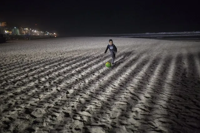 A boy plays soccer at the Mexican side of the border with the U.S. at the Pacific Ocean, Tijuana, Mexico, Friday, November 16, 2018. With about 3,000 Central American migrants having reached the Mexican border across from California and thousands more anticipated, the mayor of Tijuana said Friday that the city was preparing for an influx that will last at least six months and may have no end in sight. (Photo by Rodrigo Abd/AP Photo)