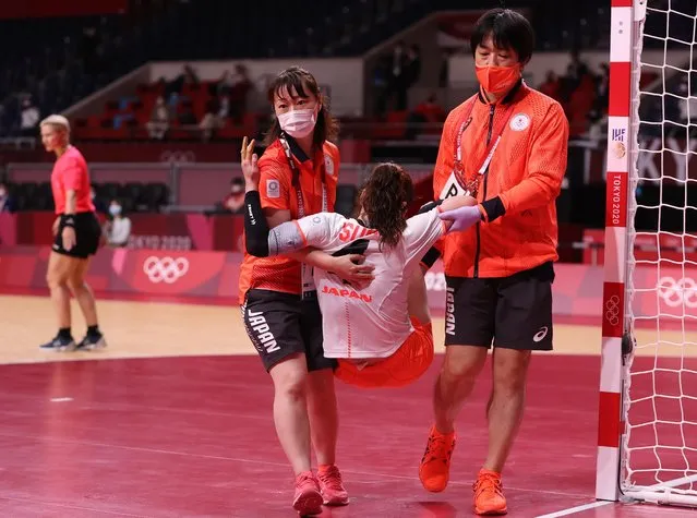 Japan's right back Yui Sunami (C) is carried after being injured during the women's preliminary round group A handball match between Japan and Montenegro of the Tokyo 2020 Olympic Games at the Yoyogi National Stadium in Tokyo on July 27, 2021. (Photo by Gonzalo Fuentes/Reuters)
