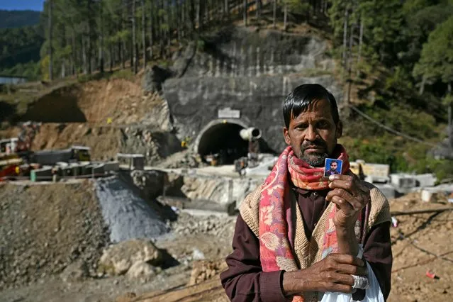 Choudhary, shows a picture of his son Manjeet Kumar trapped in the Silkyara under construction road tunnel, days after it collapsed in the Uttarkashi district of India's Uttarakhand state on November 21, 2023. Forty-one Indian workers trapped in a collapsed road tunnel for 10 days were seen alive on camera on November 21, for the first time, looking exhausted and anxious, as rescuers attempted to create new passageways to free them. (Photo by Arun Sankar/AFP Photo)
