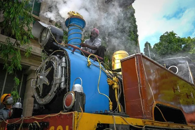 Workers perform restoration work on a 1903 steam locomotive “PL 691” kept on display at southern railway headquarters in Chennai on August 6, 2021. (Photo by Arun Sankar/AFP Photo)