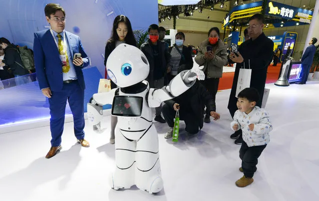 A child interacts with an intelligent robot “Dayou” during 2023 World 5G Convention at Zhengzhou International Convention and Exhibition Center on December 6, 2023 in Zhengzhou, Henan Province of China. (Photo by Zhang Tao/VCG via Getty Images)