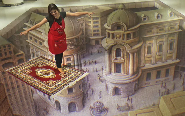 An Indonesian woman poses with a 3D illusionary art during a Trick Art exhibition in Jakarta, Indonesia, Tuesday, December 17, 2013. (Photo by Tatan Syuflana/AP Photo)