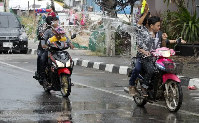 Motorcyclists are showered with water during the Songkran festival to celebrate the Thai New Year on  Samui Island in Surat Thani province, Thailand, Monday, April 13, 2015. (Photo by Mark Baker/AP Photo)