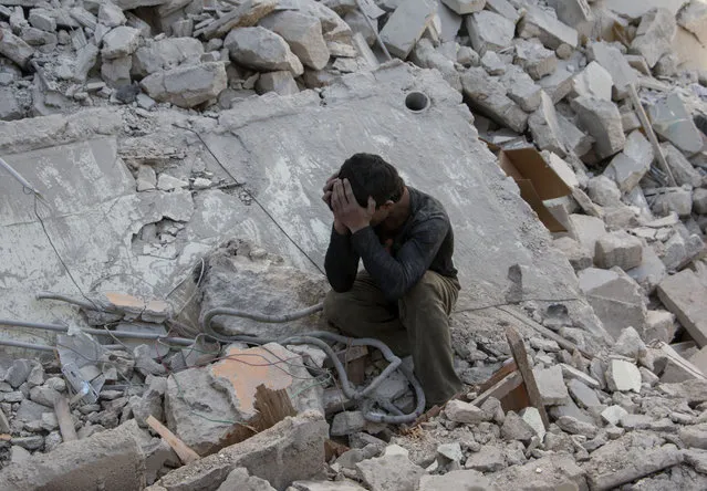 A Syrian boy mourns in the rubble of a building following a reported air strike by government forces on the rebel held area in the east of the northern Syrian city of Aleppo on April 13, 2015. (Photo by Karam Al-Masri/AFP Photo)