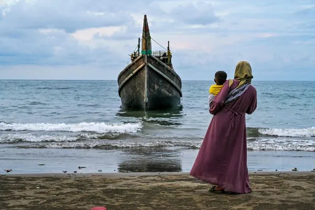 A Rohingya refugee woman with her child stands at the Laweueng beach in Pidie district of Aceh province, on December 10, 2023. More than 300 Rohingya refugees, mostly women and children, were stranded on the coast of western Indonesia on December 10 after being adrift at sea for weeks, the latest in the biggest wave of arrivals since 2015. (Photo by Chaideer Mahyuddin/AFP Photo)