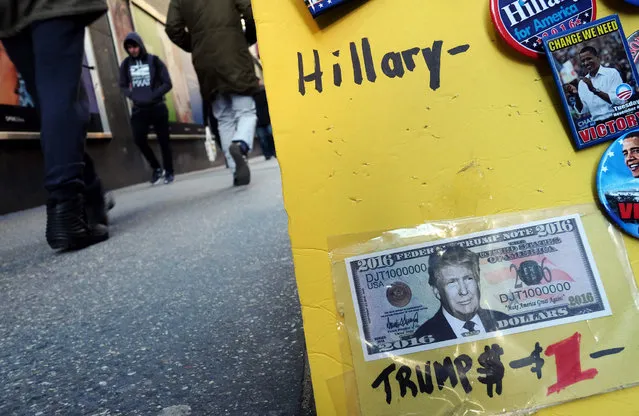 A fake dollar bill with US Republican presidential candidate Donald Trump's picture on it is displayed for sale with other electoral items at a roadside stall as pedestrians walk past in New York on February 26, 2016. White House hopefuls Ted Cruz and Marco Rubio unleashed a barrage of attacks against Donald Trump during raucous Republican debate on February 25, as they sought to halt the billionaire frontrunner's seemingly relentless march to the party's nomination. (Photo by Jewel Samad/AFP Photo)