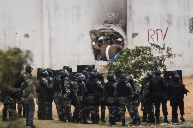Inmates, top, watch as police officers enter the Alcacuz prison amid tension between rival gangs in Nisia Floresta, near Natal, Brazil, Saturday, January 21, 2017. Military police took control of the prison in northeastern Brazil after fighting between rival gangs left 26 inmates dead, the latest in a spate of violence in the country's penitentiaries. (Photo by Felipe Dana/AP Photo)